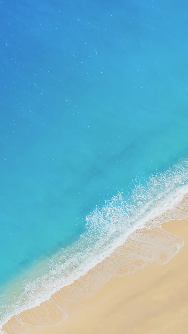 高空视角澄澈绿松石色海面海浪轻抚米黄色海滩摄影