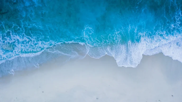 俯拍湛蓝海浪冲刷白沙滩极简风景